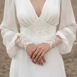 Ivoorkleurige kanten trouwjurk met lange mouwen en sleep met knoopjes op de rug