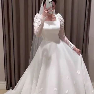 Bescheiden witte A-lijn trouwjurk met lange mouwen en tule tot op de grond